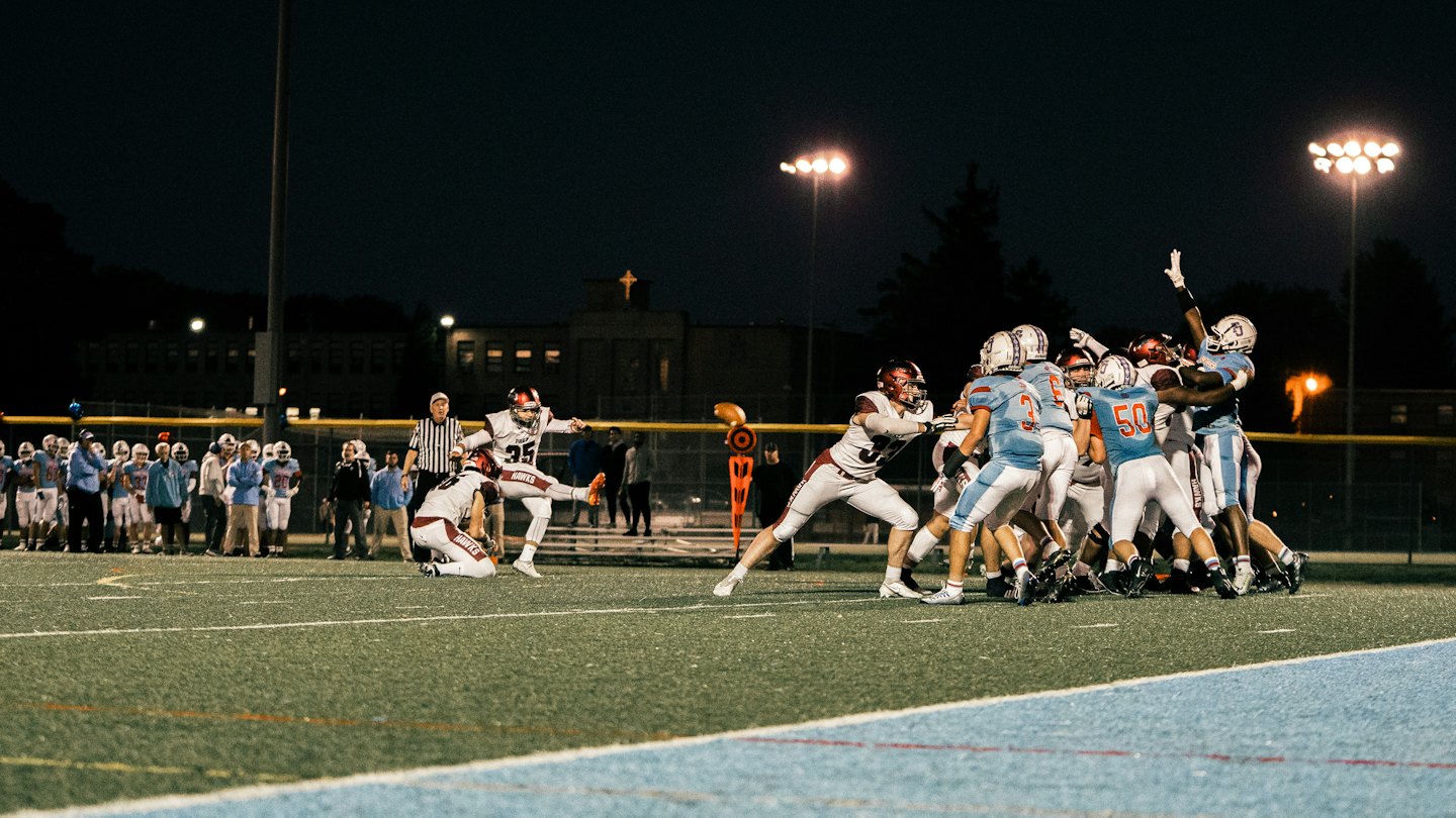 Football players compete during a night game on the field.