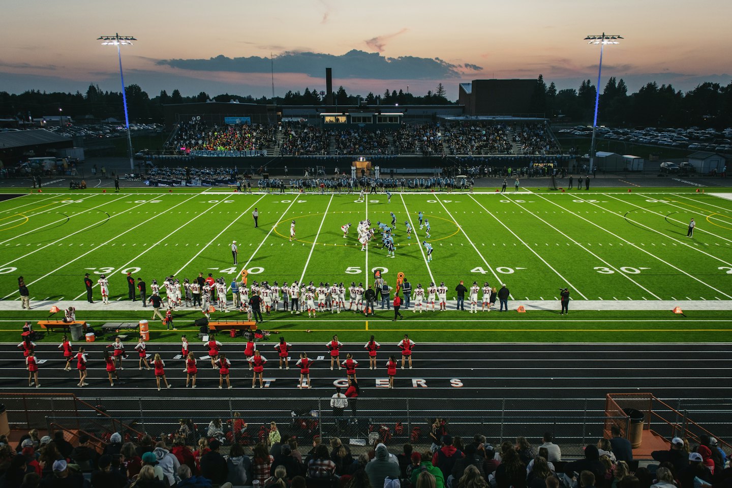 Aerial view of a high school football game at dusk.
