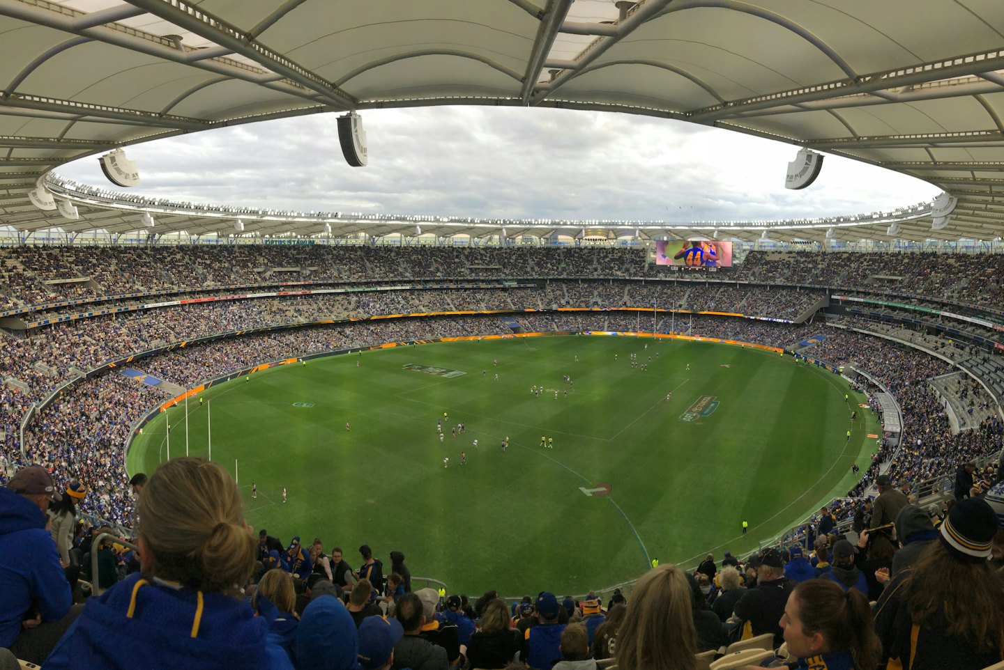 Spectators fill the tiered seating at a large sports stadium.