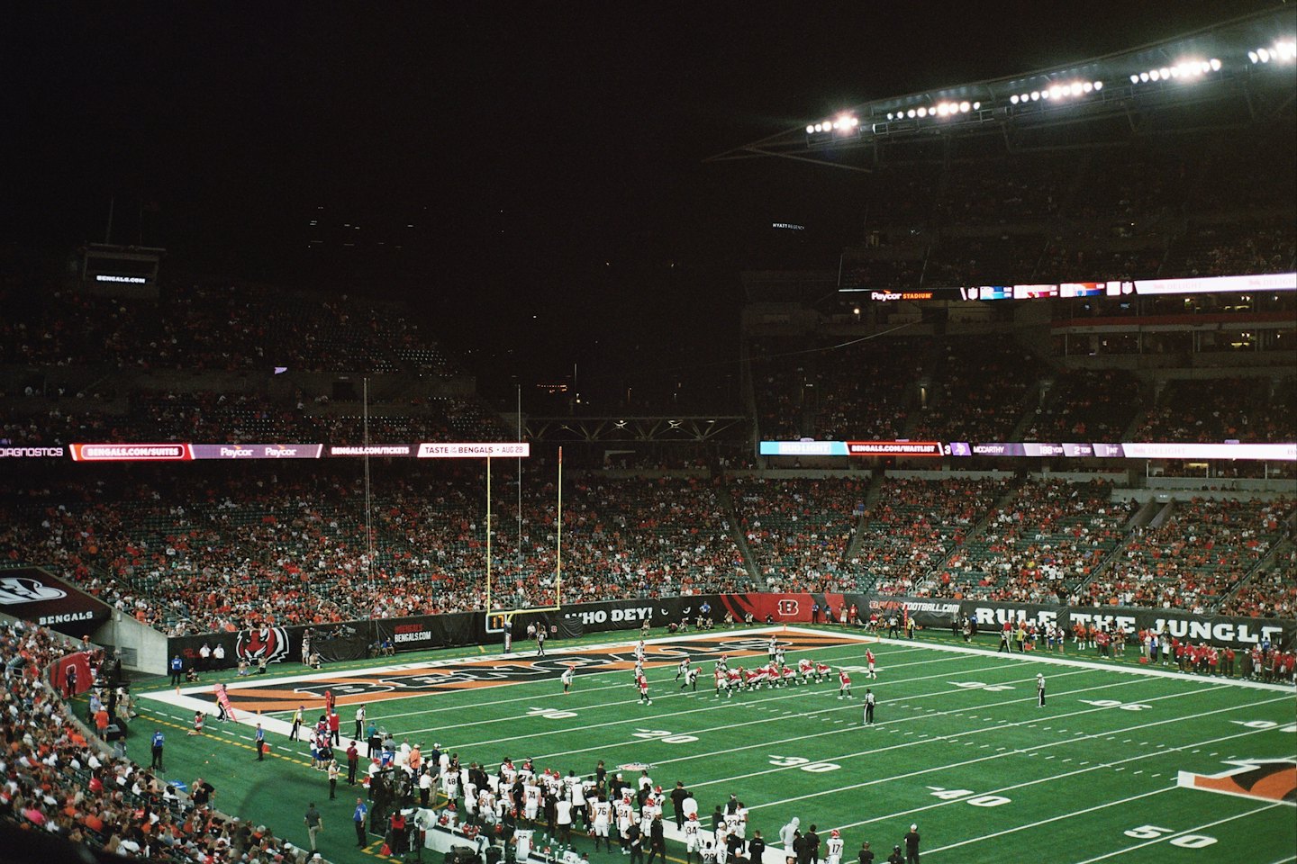 Football players compete on a stadium field before a crowd.