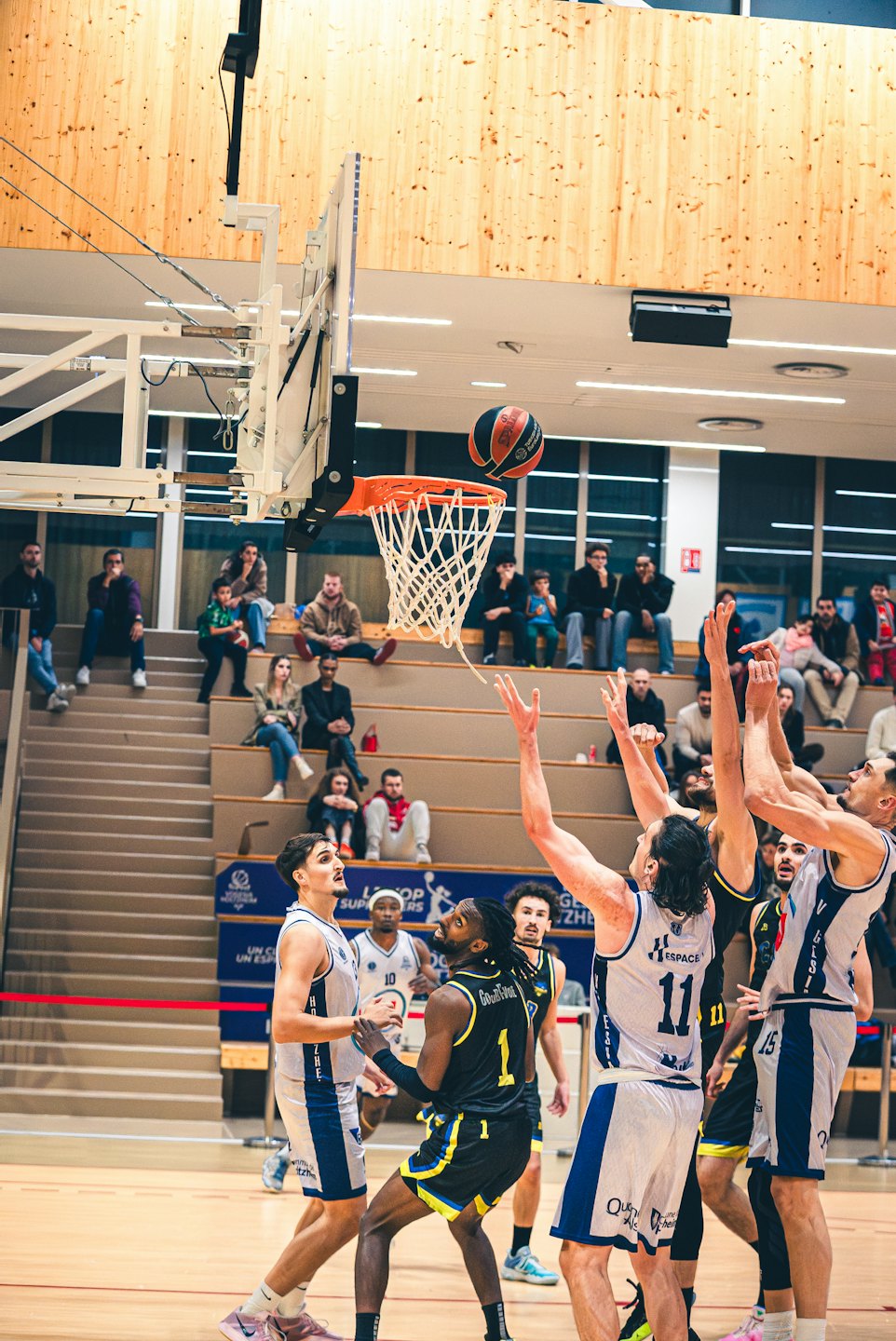 Basketball players fight for the ball near the hoop during a game.